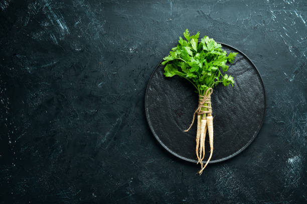 istock Root parsley and parsley on a black background. Top view. Free space for your text. 1154397096