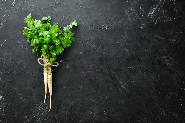 istock Root parsley and parsley on a black background. Top view. Free space for your text. 1154397204