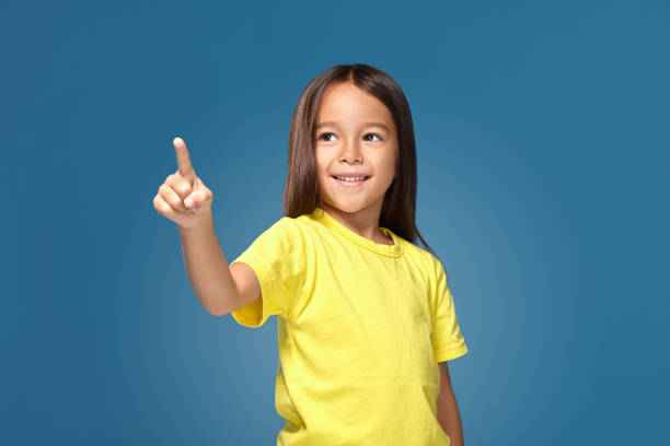 istock Cute girl shows finger on blue background 1154405429