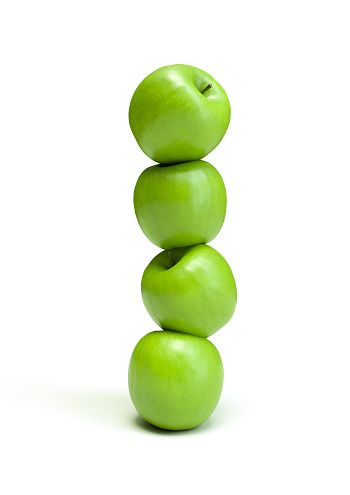Stacked green apples. Modern food art on a white background.