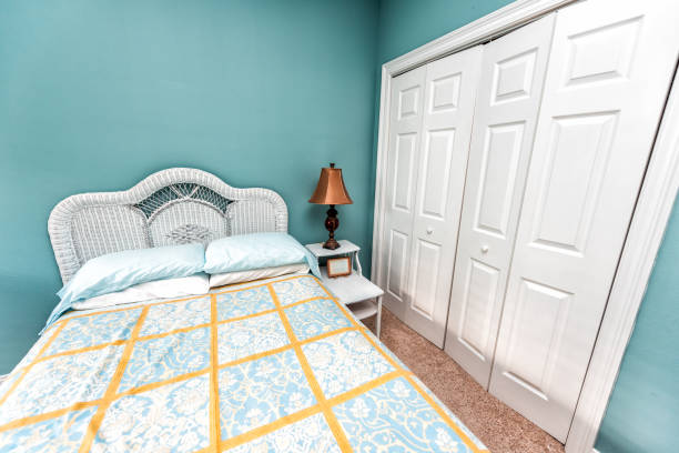 istock Clean bed linen with headboard nightstand table and lamp with vintage beach theme decorative blue green pillows in bedroom in staging model home house by closet 1154406919