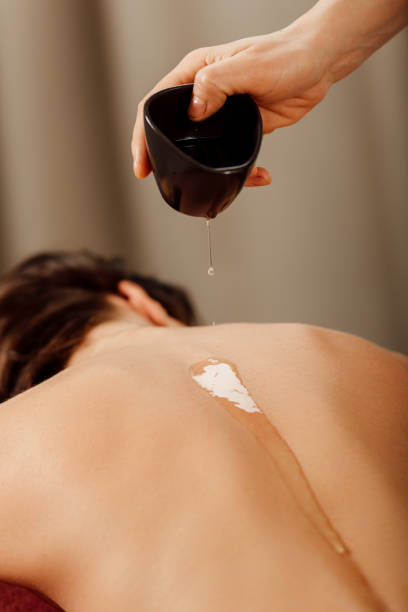 istock partial view of masseur pouring essential oil on back 1154407289