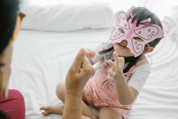 A child a girl in a pink jacket holds a white butterfly in her hand.