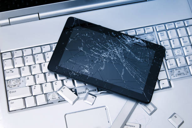 istock A silver laptop with a broken keyboard, tablet with a cracked display and black phone. A close-up picture of part of broken laptop and cracked screen on a tablet. 1154411086