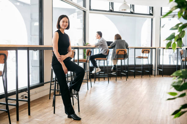 istock Elegant woman sitting on stool in open plan office 1154411522