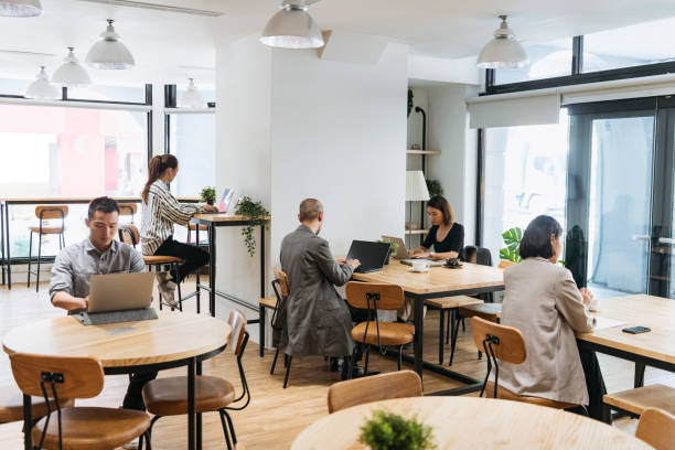 freelances travaillant sur des ordinateurs dans l’espace de coworking moderne - cotravail photos et images de collection