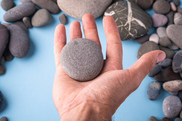 istock Pebble stone hold in hand on blue background with pebbles 1154413289
