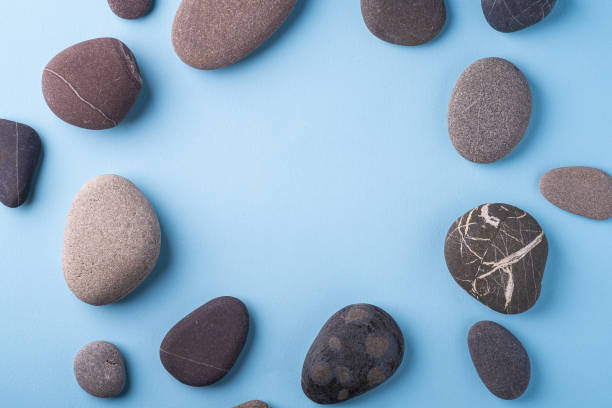 istock Copy space circle of pebbles summer background top view on blue background 1154413435
