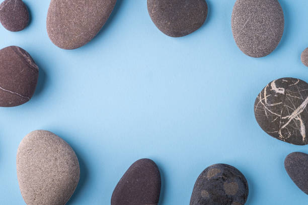 istock Copy space circle of pebbles summer background top view on blue background 1154413462
