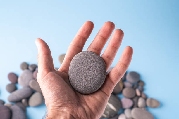 Pebble stone hold in hand on blue background with pebbles