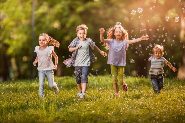 istock Carefree children having fun while running among bubbles in springtime. 1154414150