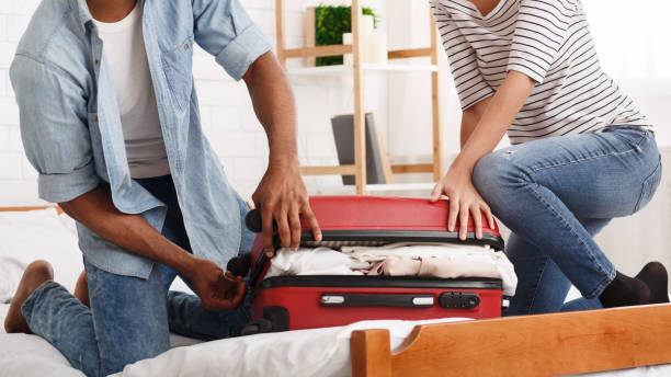 istock Packing suitcase. Couple trying to close valise 1154415762