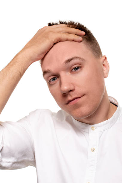 istock Charming handsome young man in a white shirt is making faces, while standing isolated on a white background 1154416105