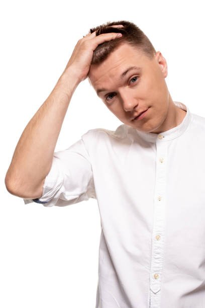 istock Charming handsome young man in a white shirt is making faces, while standing isolated on a white background 1154416131