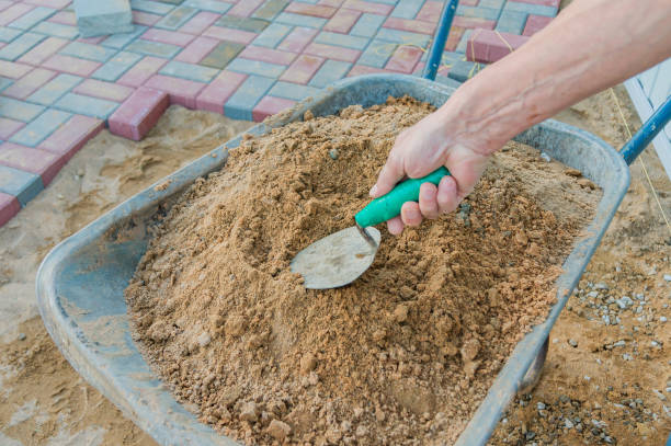 istock Worker laying red and gray concrete paving blocks. Road Paving, construction. 1154417209