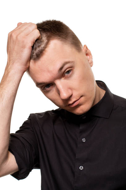 istock Handsome young man in a black shirt is making faces, while standing isolated on a white background 1154417500