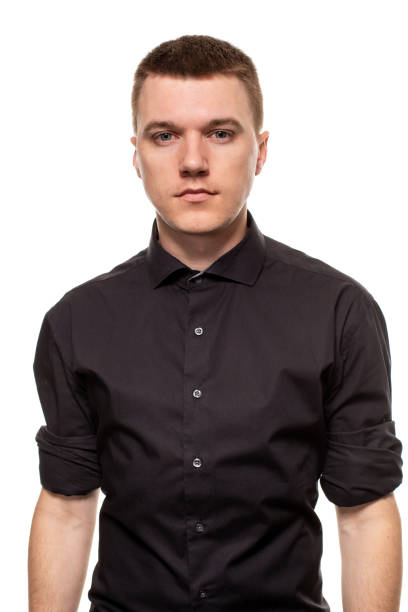 istock Handsome young man in a black shirt is making faces, while standing isolated on a white background 1154417503