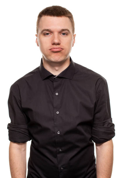 istock Handsome young man in a black shirt is making faces, while standing isolated on a white background 1154417530