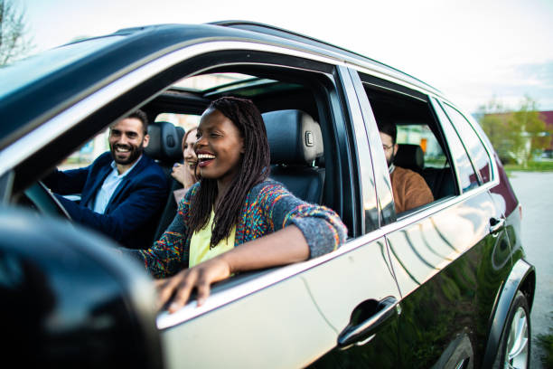 Cheerful group of multi-ethnic friends on road trip Multi-ethnic group of cheerful friends sitting in a car, riding and having fun on beautiful summer day back seat photos stock pictures, royalty-free photos & images