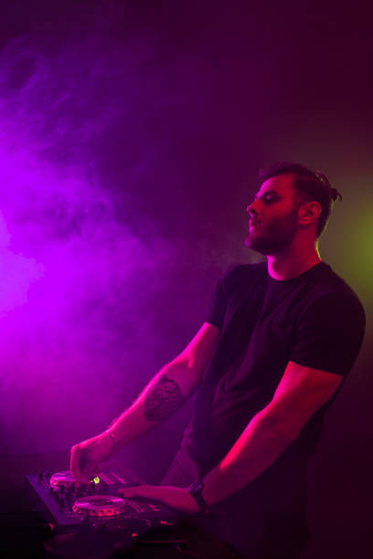 istock Attractive young DJ playing on turntables with color light effects 1154422308