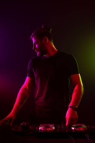istock Attractive young DJ playing on turntables with color light effects 1154422425