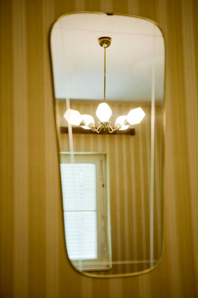 60's or 70's interior: Lamp in a mirror, wallpaper with stripes in beige-yellow.