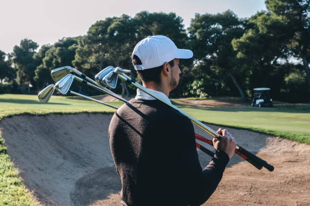 istock Profile of a golf player observing a golf course with several golf sticks on his shoulders 1154425032
