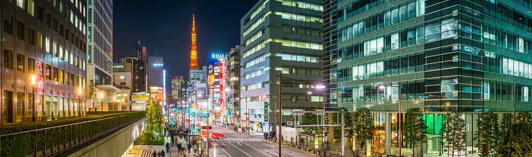 Panoramic view across the busy streets of downtown Tokyo through the neon and glass canyon of skyscrapers to Tokyo Tower in the heart of Japan’s vibrant capital city at night.