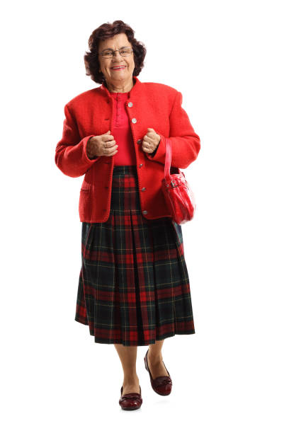 A young Asian woman is wearing a traditional Santa Claus costume, which consists of a red dress with white trim, a matching Santa hat, and a black belt. She is standing against a white background with her hands gently placed on her cheeks, smiling and looking cheerful. The festive outfit is perfect for the Christmas holiday season, capturing the joyful and celebratory spirit of the occasion.