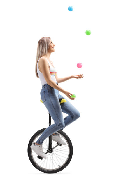 jeune femme jonglant avec des boules sur un monocycle - unicycling photos et images de collection