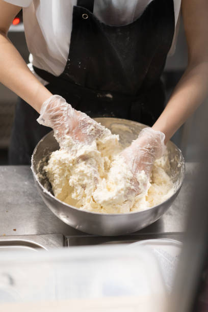 o cozinheiro chefe mestre prepara uma sobremesa doce para a produção de doces. massa de mistura e creme para o bolo em uma bacia profunda. - cake making mixing eggs - fotografias e filmes do acervo