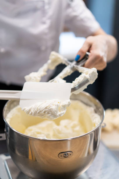 master chef prepares a sweet dessert for the production of sweets. mixing dough and cream for the cake in a deep bowl. - cake making mixing eggs imagens e fotografias de stock