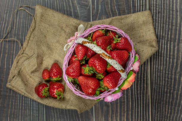 istock Strawberries in a small basket on the wooden table. 1154430515
