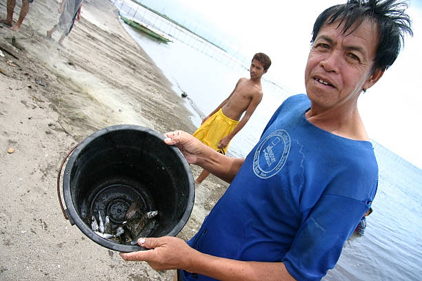 Tanjay, Negros Oriental, Philippines - July 25, 2005:  A Filipipino fisherman shows his paltry catch at a local Tanjay beach, on Negros Oriental, Philippines on July 25, 2005.