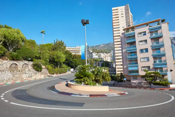 Photo of Monte Carlo street curve with open-wheel single-seater racing car red and white signs in a sunny summer day in Monte Carlo, Monaco