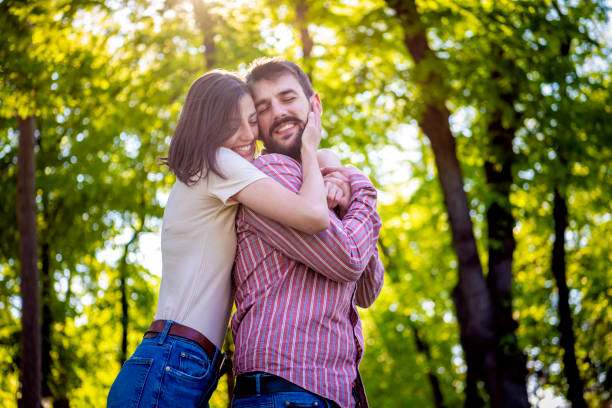 istock Pure fun. Young beautiful couple bonding to each other while walking in the park .Falling deeper in love every moment they're together. Young smiling couple in hug standing at park.Young beautiful romantic couple in love hugging at public park. 1154436501