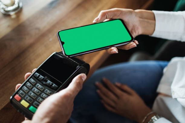 Close up hand making NFC payment using smart phone Customer making payment in modern cafe or restaurant by smartphone using NFC (near field communication) wireless technology. Close up shot. Consumer technology concept. quick service restaurant cashier stock pictures, royalty-free photos & images