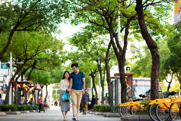 istock Couple is walking on footpath along trees in city 1154436842