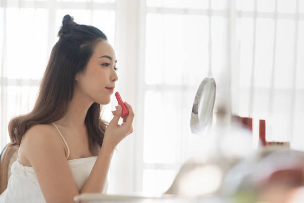 istock Attractive Asian Female applies lipstick 1154437921