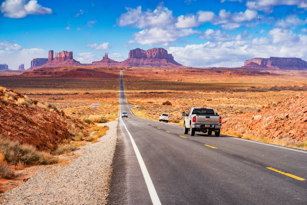 Cars drive at Forrest Gump Point in Monument Valley Utah USA Cars drive at Forrest Gump Point in Monument Valley, Utah, USA on a sunny day chevrolet silverado stock pictures, royalty-free photos & images