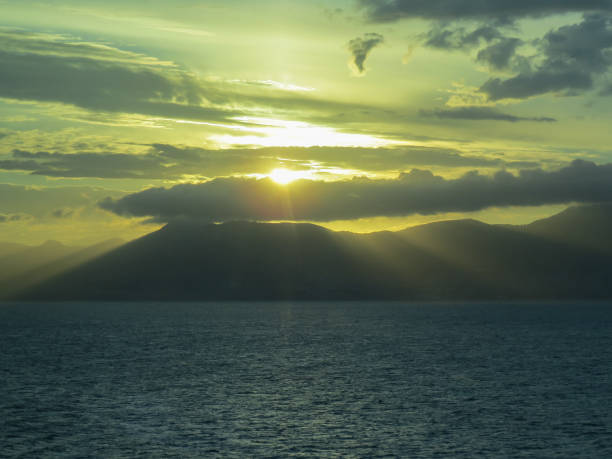 istock Background. Sunset. Sea and mountains. The sun's rays make their way through the clouds. 1154445391