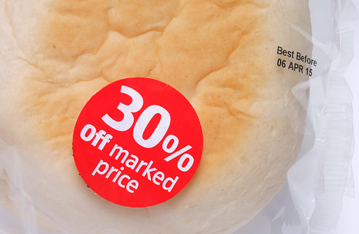 Discount sticker attached to cellophane bread packaging. 30 per cent off marked price. Best before date printed on packaging