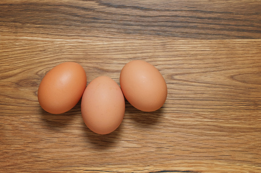 Three brown hens eggs shot from above on a wooden table
