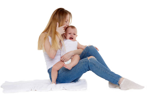 Asian mother and baby laugh together at home. Asia mom holdind infant and sitting on white bed in living room at house  having fun together.