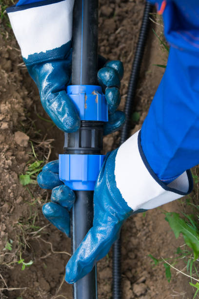 istock hands in rubber gloves connect thick long pipes for water 1154448914
