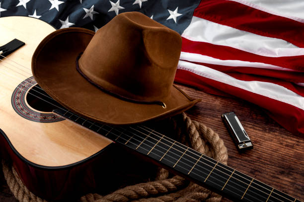 amerykańska kultura, życie na ranczo i temat koncepcji muzyki country z kowbojskim kapeluszem, flagą usa, gitarą akustyczną, harmonijką i lasso linowym na drewnianym tle w starym salonie - cowboy hat wild west hat wood zdjęcia i obrazy z banku zdjęć