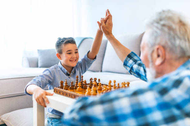 istock Smiling middle aged man teaching grandson to play chess at home 1154454452