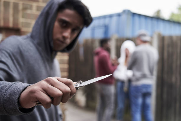 adolescent garçon dans urban gang pointant le couteau vers la caméra - violence black men women photos et images de collection