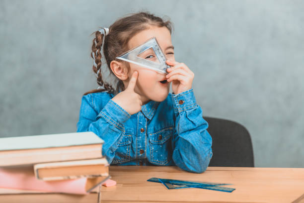 istock Funny little inquisitive girl playing around during the learning process, looking through the triangle. 1154456316