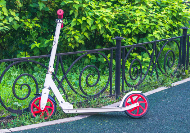 istock White and red scooter leaned on fence in park 1154459039